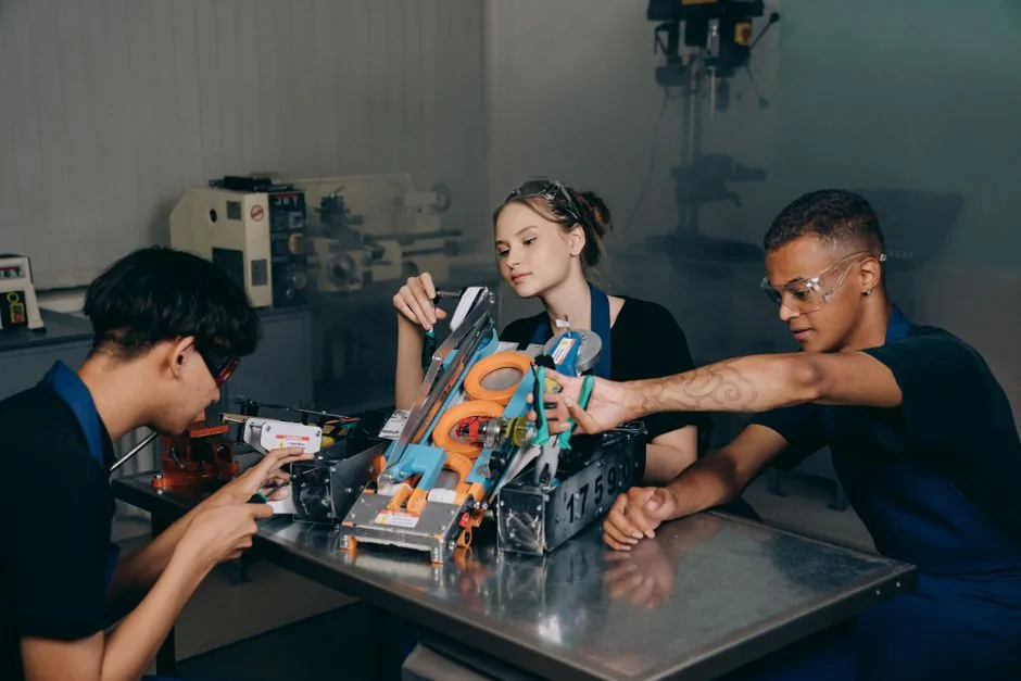 Engineering students assembling a robotic arm prototype at a workbench