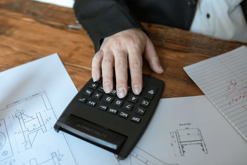 Engineer using a calculator over printed technical drawings