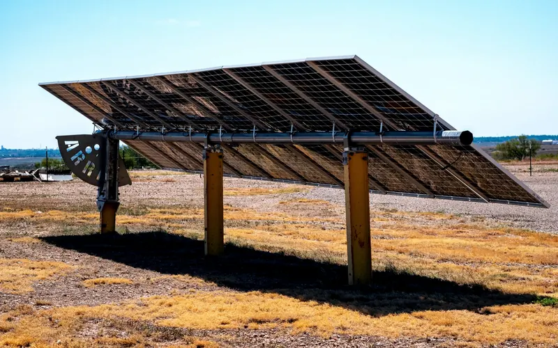 Ground-mounted solar array standing on dry, dusty farmland