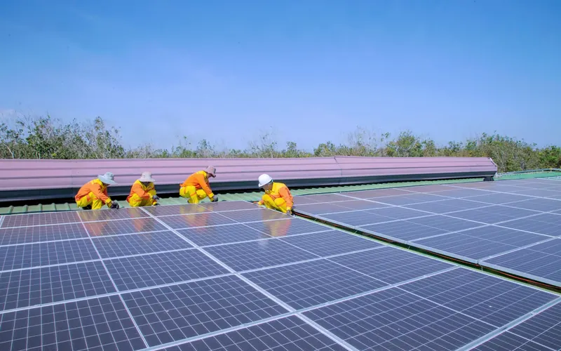 Installation crew fixing rows of solar panels on a flat rooftop