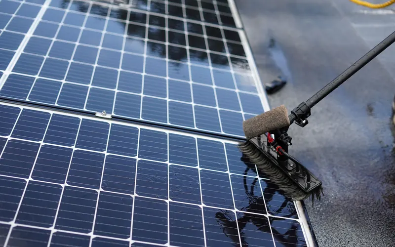 Soft-bristle brush washing dust off solar panels with water